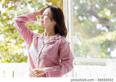 A refreshing woman standing by the window and bathing in the morning light 86688083