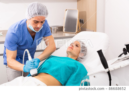 Woman receiving body ultrasound lifting procedure Woman receiving body ultrasound lifting procedure 86688652