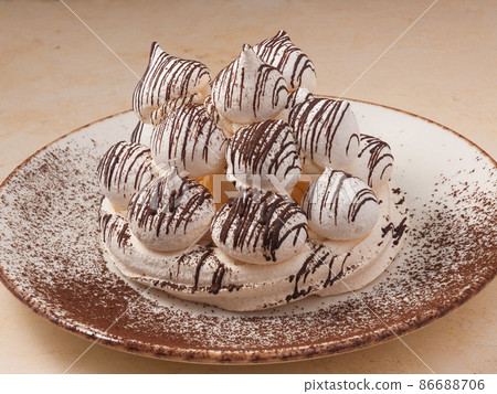 meringue cake poured with chocolate on a light plate 86688706