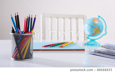 Closeup of color pencils, wax chalks, globe and notebooks. Closeup of color pencils, wax chalks, globe and notebooks. 86688835