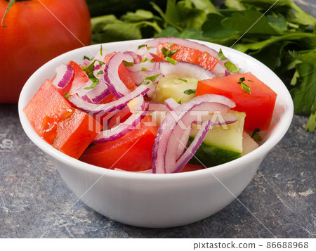 vegetable salad of cucumbers tomatoes and onions in a white bowl. Close up 86688968
