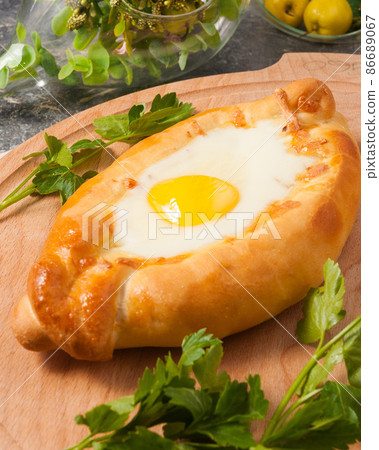 Ajarian khachapuri on a wooden Board decorated with parsley Ajarian khachapuri on a wooden Board decorated with parsley 86689067