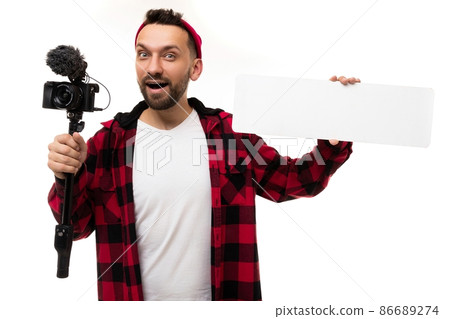 young stylish blogger with a video camera with a microphone demonstrates a sign for copy-space young stylish blogger with a video camera with a microphone demonstrates a sign for copy-space 86689274