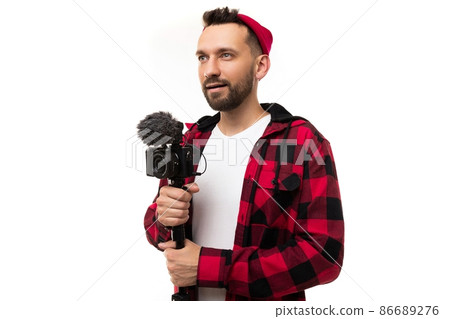 blogger in a half-turn with a camera and a microphone in his hands on a white background 86689276