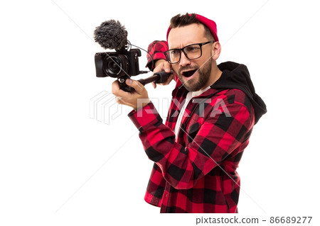 young male blogger filming a story on a video camera with a microphone 86689277