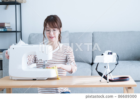 一位女士一邊用縫紉機縫製一邊拍攝視頻 86689300