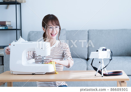 A woman shooting a video while sewing with a sewing machine A woman shooting a video while sewing with a sewing machine 86689301
