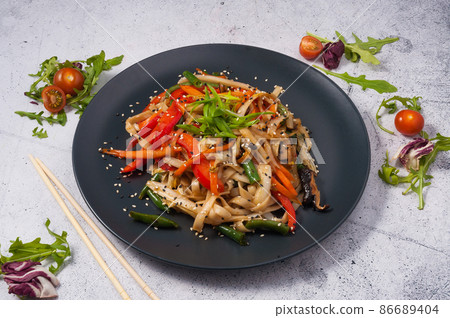Udon noodles with vegetables on a black plate. Asian cuisine 86689404