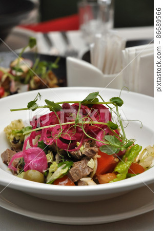 salad with vegetables and boiled beef on a white plate in a restaurant salad with vegetables and boiled beef on a white plate in a restaurant 86689566