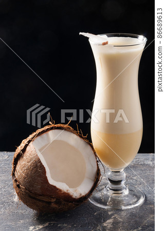 Pina colada decorated with coconut on a black background Pina colada decorated with coconut on a black background 86689613