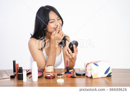 woman applying make up powder and blush on her cheeks woman applying make up powder and blush on her cheeks 86689626