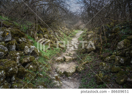 Trail with old stone ruins in the rock Cave city Chufut-Kale in Bakhchysarai, Crimea Trail with old stone ruins in the rock Cave city Chufut-Kale in Bakhchysarai, Crimea 86689651