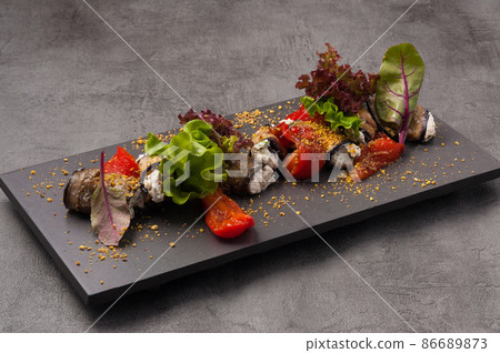 eggplant rolls with cheese garnished with dried tomatoes and herbs 86689873