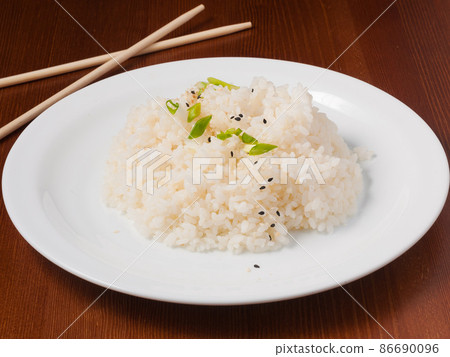rice is garnished with green onions and sesame seeds on a white plate rice is garnished with green onions and sesame seeds on a white plate 86690096
