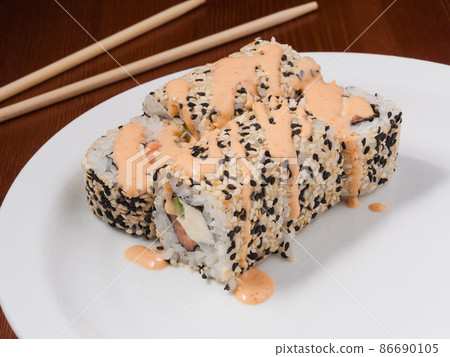 spicy sushi roll with salmon on a white plate spicy sushi roll with salmon on a white plate 86690105