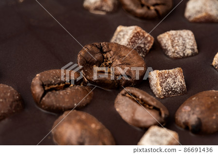 Close up of dark chocolate bar with coffee beans and candied fruit Close up of dark chocolate bar with coffee beans and candied fruit 86691436