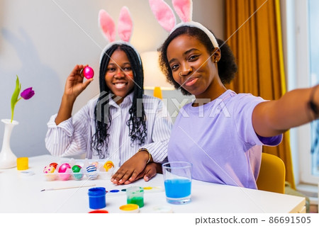 two polyethnic pretty woman taking selfie photo on camera of smartphone and preparing to easter together two polyethnic pretty woman taking selfie photo on camera of smartphone and preparing to easter together 86691505