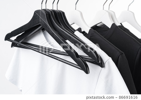 Black and white T-shirts on hangers on metal rack isolated on white Black and white T-shirts on hangers on metal rack isolated on white 86691616