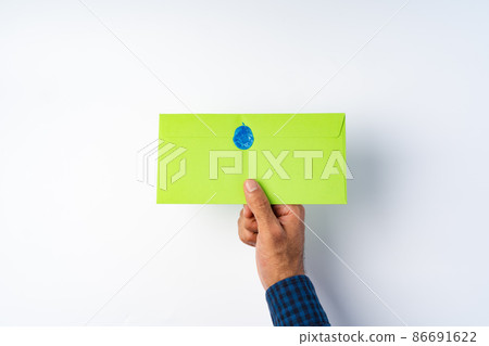 Male hand holding closed envelope above the white surface Male hand holding closed envelope above the white surface 86691622