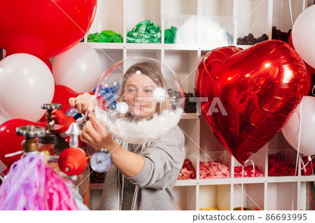 Woman inflates helium balloon with white feathers inside. valentine's day 86693995