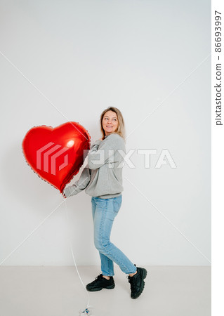 blonde woman large red heart-shaped balloon white background. valentine's day 86693997