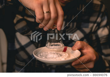Bartender dipping shot glass in salt preparing for serving of tequila Bartender dipping shot glass in salt preparing for serving of tequila 86694076