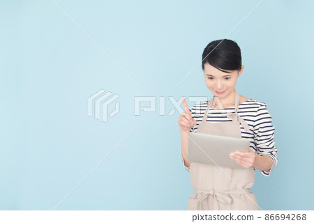 A woman in an apron operating a tablet 86694268