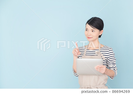 A woman in an apron operating a tablet 86694269