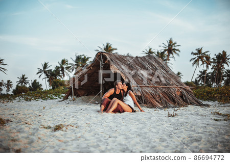Loving couple on the beach near the hut. Honeymoon of newlyweds. Guy and girl at sunset by the sea. Man and woman kissing at sunset. Couple travels. Holiday in GOA. Lovers on the island. Voucher Loving couple on the beach near the hut. Honeymoon of newlyweds. Guy and girl at sunset by the sea. Man and woman kissing at sunset. Couple travels. Holiday in GOA. Lovers on the island. Voucher 86694772