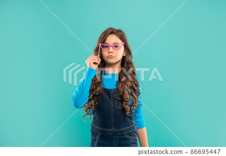 arrogant kid with long curly hair on blue background. arrogant kid with long curly hair on blue background. 86695447