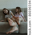 Two younger sisters are playing on the couch. Cozy home communication 86696594