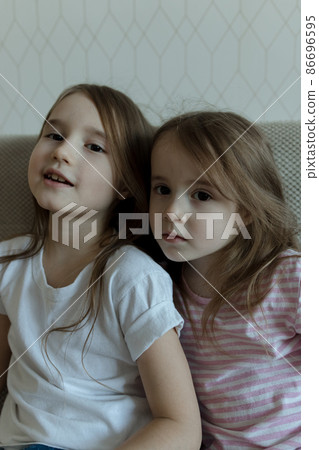 Two younger sisters are playing on the couch. Cozy home communication Two younger sisters are playing on the couch. Cozy home communication 86696595