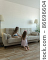 Two little sisters are playing on the sofa. Cozy home entertainment 86696604