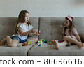 Two little sisters are playing on the sofa. Cozy home entertainment 86696616