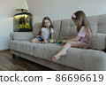 Two little sisters are playing on the sofa. Cozy home entertainment 86696619