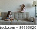 Two little sisters are playing on the sofa. Cozy home entertainment 86696620