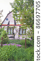 Pink country house with blooming saxifrage and juniper in the front garden. 86697705