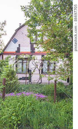 Pink country house with blooming saxifrage and juniper in the front garden. Pink country house with blooming saxifrage and juniper in the front garden. 86697705