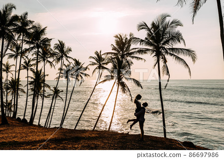 A couple in love meets a sunset on the sea among the palm trees. Man and woman at sunset. Honeymoon on the Islands. Honeymoon trip. Happy loving couple. Silhouette lovers. Wedding travel. Sri lanka 86697986