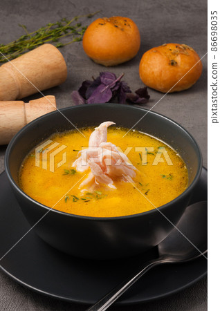 chicken soup with rolls in a dark bowl chicken soup with rolls in a dark bowl 86698035
