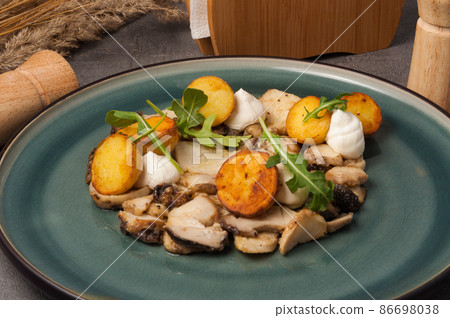 fried porcini mushrooms with new potatoes garnished with arugula fried porcini mushrooms with new potatoes garnished with arugula 86698038