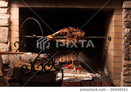 the back of a lamb on a spit with a glass of brandy 86698081
