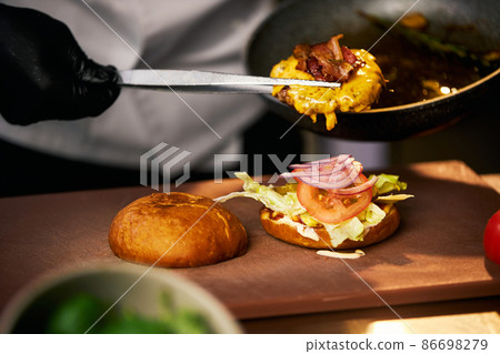 Preparing delicious grilled cheeseburger.  86698279