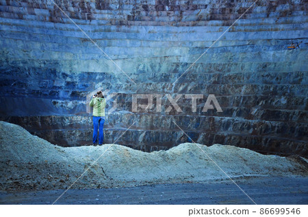 Geologist studying gigantic open cast gold and copper mine terraces. Romania Geologist studying gigantic open cast gold and copper mine terraces. Romania 86699546