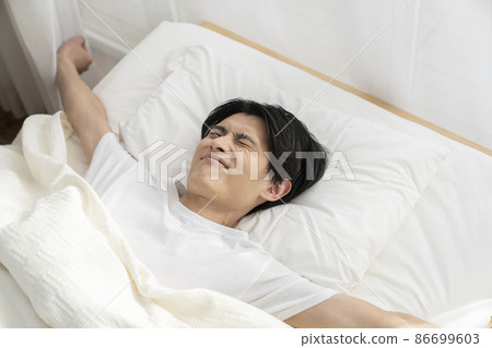 Young man stretching in bed 86699603