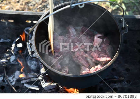 Hashed beef stewed outdoors in a Dutch oven and charcoal Hashed beef stewed outdoors in a Dutch oven and charcoal 86701898