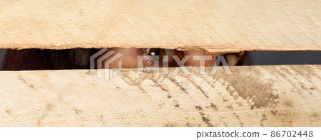 The female eye of a man looking through the gap of the fence, close-up The female eye of a man looking through the gap of the fence, close-up 86702448