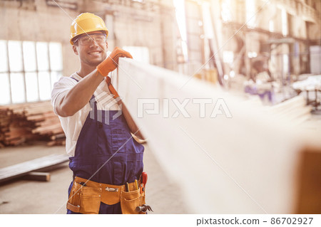 Smiling man builder carrying wooden plank at construction site 86702927