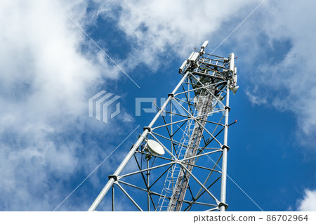 Bottom perspective pov of modern metal steel mobile 5g network wireless telecom tower against clear blue sky background on bright day. Microwave signal broadband equipment base line station mast 86702964
