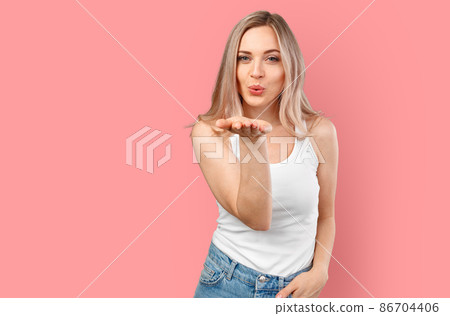 Pretty blonde woman blows kiss into camera isolated on color background. Pretty blonde woman blows kiss into camera isolated on color background. 86704406